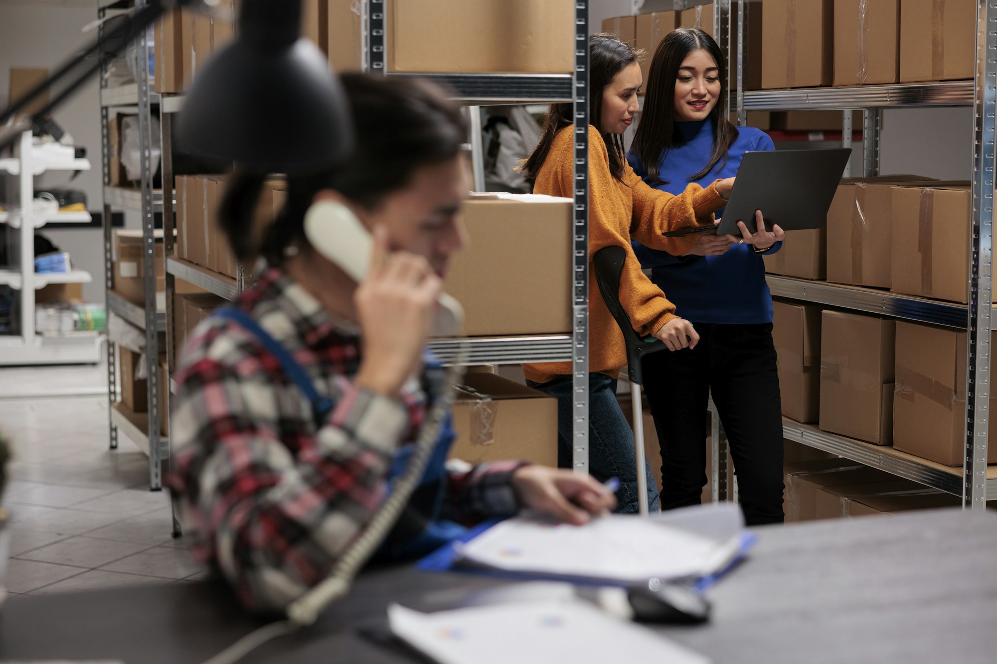 Warehouse employees using inventory management system software on laptop